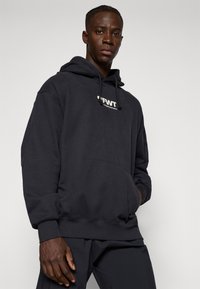 Sudadera de algodón negra con un bolsillo frontal, capucha con cordón y un logo blanco en el pecho. Cuenta con puños y dobladillo acanalados.