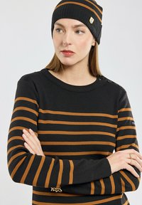 Pull en maille rayé noir et marron avec un col rond, doté de boutons aux épaules et d'une coupe ajustée. Accompagné d'un bonnet assorti.