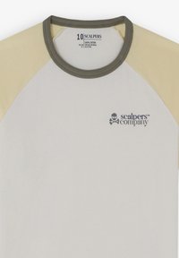 Katoenen T-shirt met een witte romp, roomkleurige raglanmouwen en een olijfgroene ribbelhals. Bevat een klein logo met een doodskopdetail op de borst.