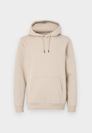Kapuć sweatshirt u svijetloj bež boji, napravljen od mekog materijala. Ima prednji džep i podesive šnure s crnim vrhovima. Rebrasti manžete.