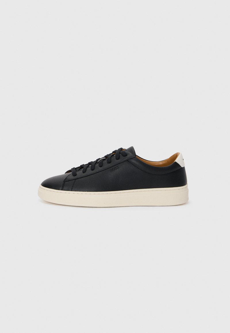 Sorte skinnesneakers med en jevn tekstur, beige gummisåle, lisser og en kontrasterende hæl aksent.