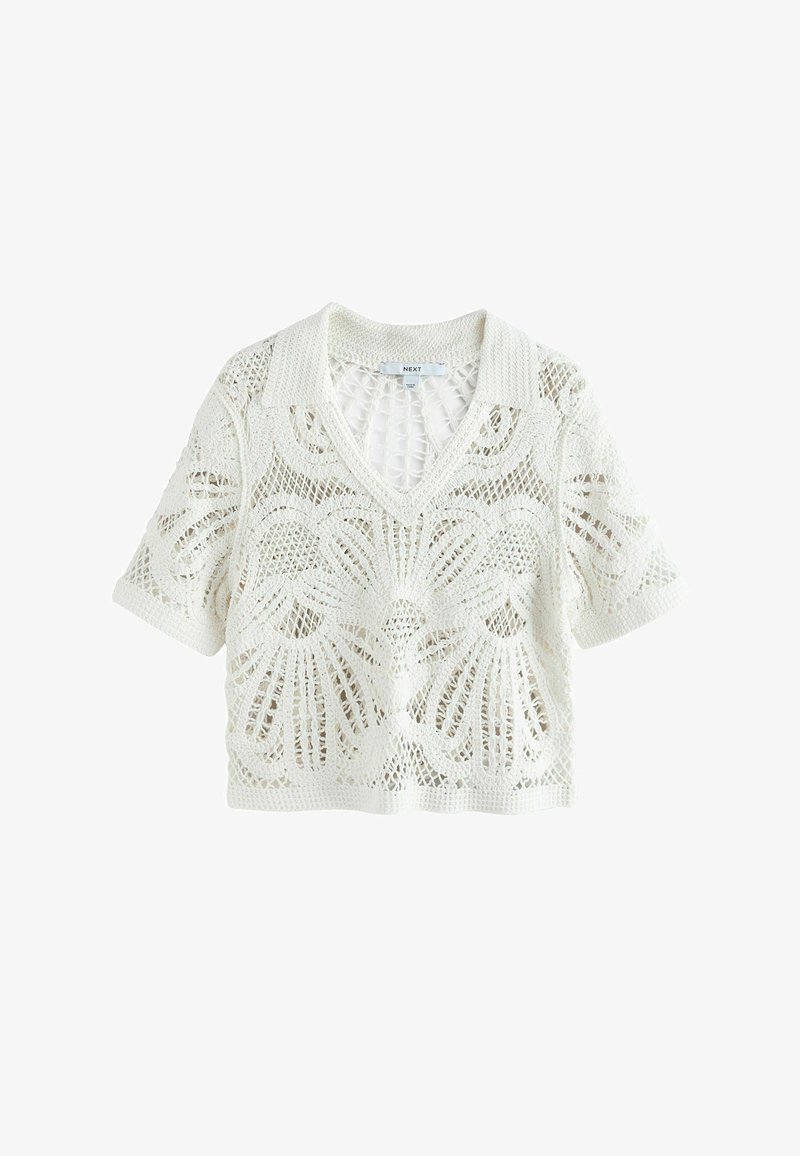 Haut blanc en crochet à manches courtes avec col, encolure en V et motif floral en dentelle sur toute la surface.