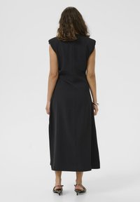 Crna haljina bez rukava s uskim korzetom, lepršavim A-linijom i duljinom do koljena. Glatka tekstura s čistim šavovima i suptilnim detaljima.