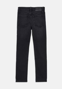 Vaqueros de mezclilla negra con corte slim, cinco bolsillos y una etiqueta de cuero con la marca en la parte trasera de la cintura. Textura suave, diseño de pierna ajustada.