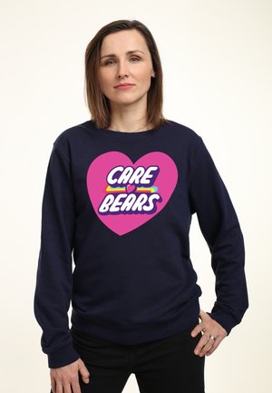 Felpa blu navy con una grande grafica a cuore rosa che presenta il testo "CARE BEARS" in bianco e colori arcobaleno. Tessuto morbido, vestibilità comoda.