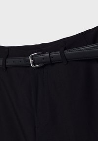 Black trousers with a smooth texture and a black leather belt featuring a silver metal buckle, showcasing belt holes and stitching details.