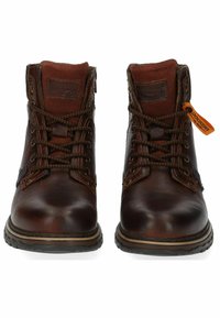 Botas de cuero marrón hasta el tobillo con puntas redondas, ojales metálicos y etiquetas amarillas contrastantes. Presentan un upper texturizado y una suela de goma de múltiples capas.