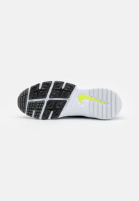 Čierno-biela podrážka športovej obuvi s textúrovaným vzorom, vybavená jasne žltým logom Nike a výraznými trakčnými prvkami.