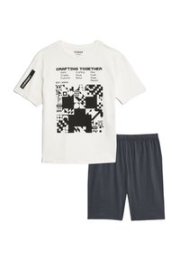 T-shirt blanc avec design graphique noir et texte, associé à un short gris foncé. Matière en coton, manches courtes, taille élastique.