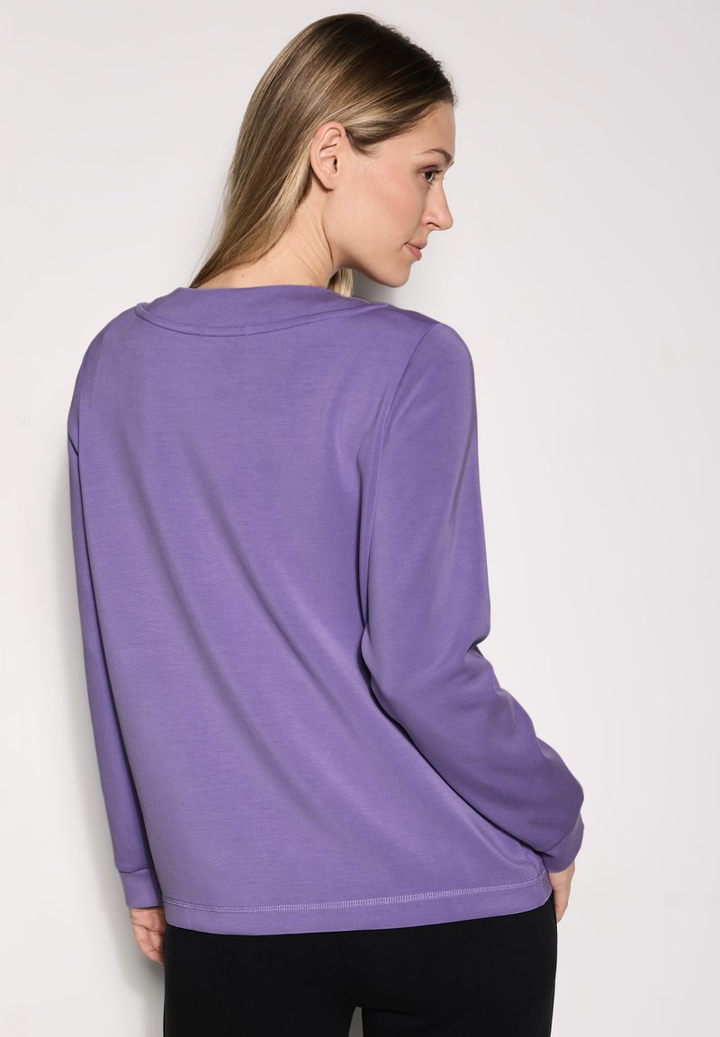 Maglietta lunga viola con collo rotondo e dettagli di cucitura subtle, realizzata in morbido tessuto, vista da dietro.