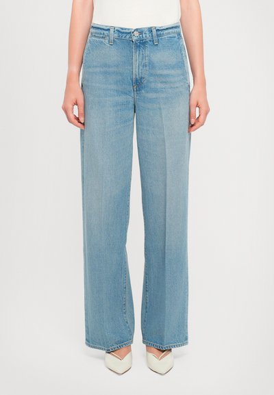 Jeans en denim bleu clair à taille large, dotés d'un design classique à cinq poches et d'un ourlet cousu. Assortis à des chaussures à bout pointu ivoire.