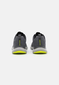 Graue Sportschuhe mit einem atmungsaktiven Mesh-Obermaterial, reflektierenden Akzenten und einer neongelben Außensohle, ausgestattet mit einer gepolsterten Zwischensohle für Unterstützung.