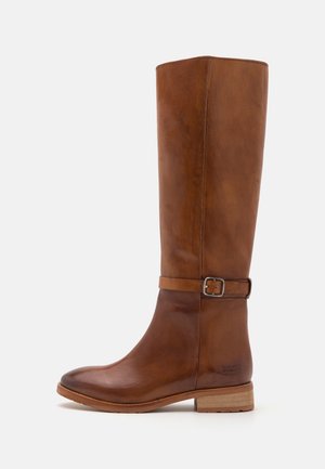 Botte haute en cuir marron avec talon bas en bois et sangle ajustable avec boucle en métal autour de la cheville.