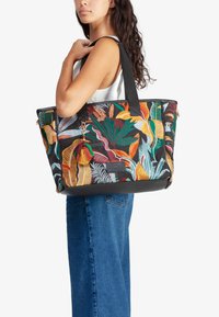 Bolso tote negro con bordado de hojas coloridas, con un fondo negro, asas dobles y un charm de borlas coloridas. Tejido texturizado.
