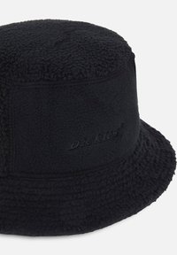 Svart bucket hat i texturerad fleece, med sydda kanter och en subtil, präglad logotyp på sidan. Rund krone, mjukt material.