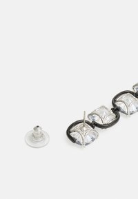 Uhani srebrne barve s prozornimi kvadratnimi kristali, zasnovani z črnimi akcenti in z zatičem, z natančno izdelanimi nastavitvami kamnov.