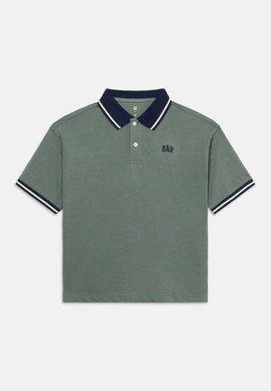 Zelena polo majica kratkih rukava s tamnoplavim ovratnikom i rubovima rukava, dva bijela pruga na ovratniku i rubovima te tamnoplavi logo "GAP" na prsima.