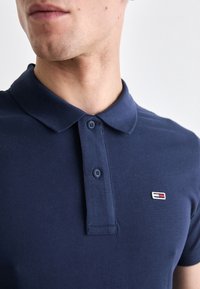 Navy blue polo shirt in a cotton blend, featuring a classic collar, two buttons, and a small multicolored logo on the chest.