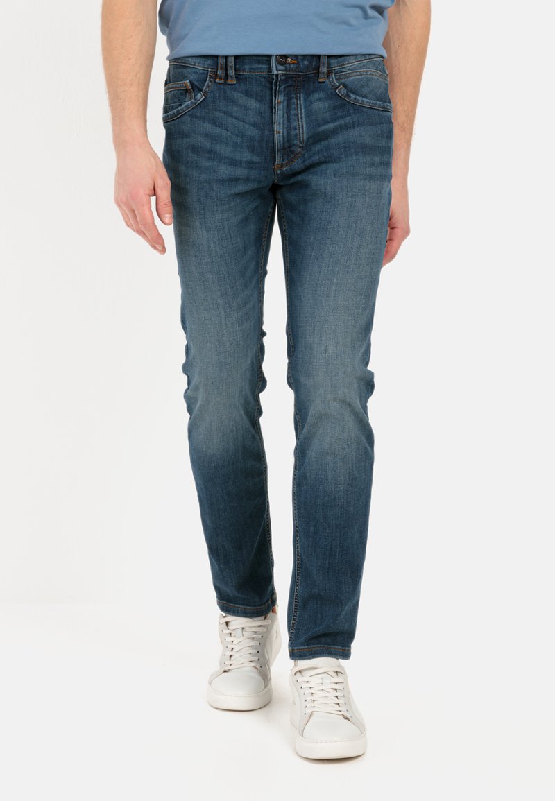 Jean en denim bleu à coupe slim, doté de cinq poches, d'une légère décoloration, d'une fermeture par bouton et de coutures décoratives sur les poches.