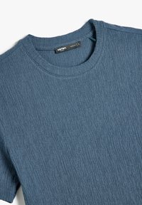 Slank-fit blå tekstureret t-shirt lavet af bomuld. Har en rund halsudskæring og subtile lodrette striber i stoffet. Letvægtig og afslappet design.