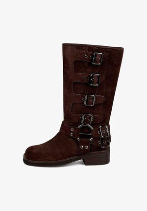 Braune Wildleder-Ankle Boots mit hohem Schaft, ausgestattet mit fünf silbernen Schnallen und einer runden Hardware-Akzent. Niedriger Blockabsatz. Flache Sohle.