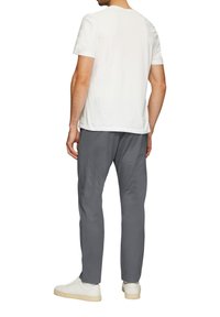Witte katoenen t-shirt met korte mouwen, gecombineerd met grijze broek en witte sneakers. Focus op een relaxte pasvorm en een simpel ontwerp zonder patronen.