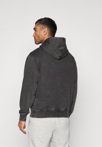 Sweatshirt à capuche gris foncé, doté d'une texture douce, de poignets et d'une taille côtelés, avec une coupe décontractée et une vue de dos de la capuche.