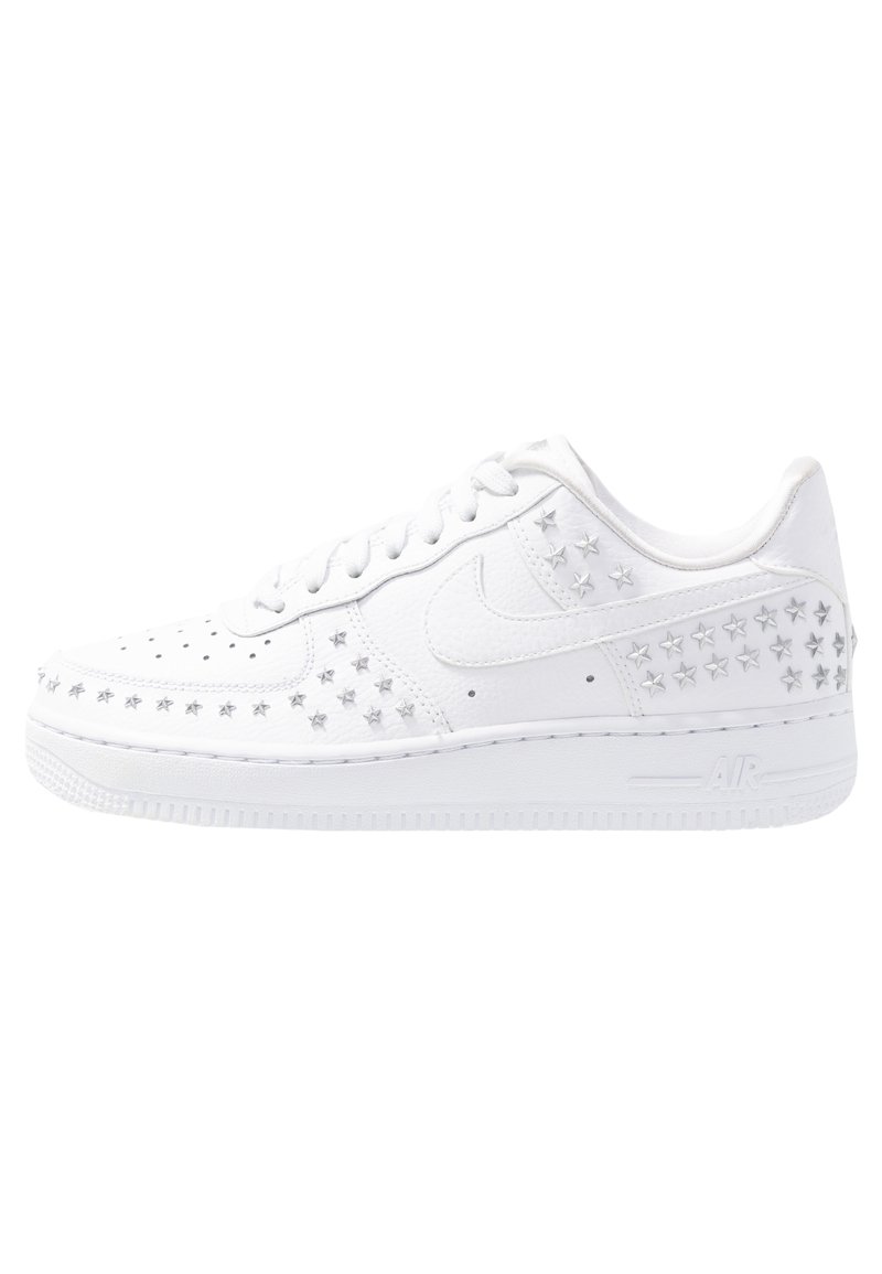 Weiße Sneaker aus Leder mit sternförmigen silbernen Nieten an den Seiten, Löchern nahe der Zehen und einer strukturierten Gummisohle.