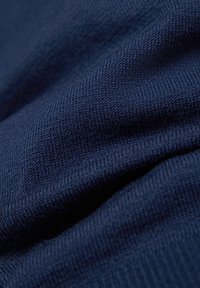 Marineblaue Baumwollstoffe mit glatter Textur und geripptem Strickmuster, die sanfte Falten und Schatten durch Drapierungen zeigen.