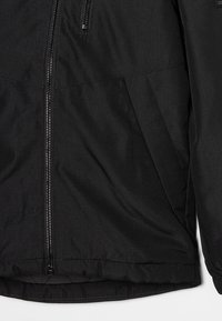 Czarna kurtka z zamkiem z przodu, bocznymi kieszeniami i elastycznym wykończeniem widoczna na prostym tle.