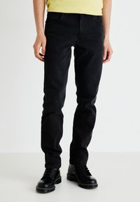Zwarte spijkerbroek van denim, slim fit met een rechte pijp, met voorzakken en gedragen met zwarte veterschoenen.