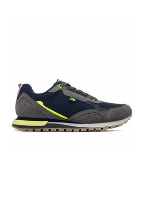 Vista lateral de una zapatilla baja con ante gris, tela azul marino, detalles en amarillo neón, suela negra y blanca y cordones grises.