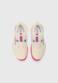 Baskets de sport beiges avec des accents roses et des détails violets, dotées d'une boîte à orteils perforée, de lacets plats et d'un logo Asics.