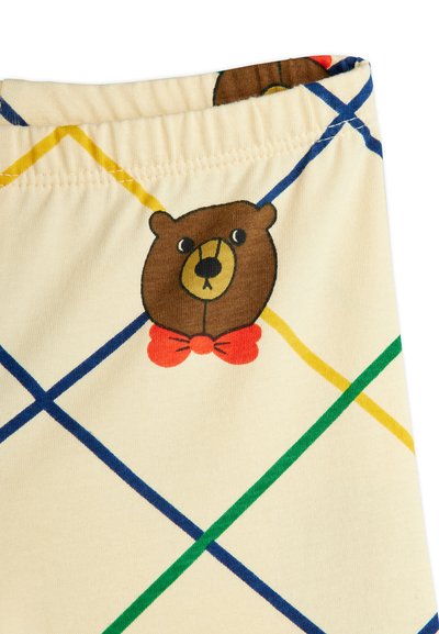Tela de algodón con un fondo de color crema claro y un estampado de un oso que lleva una pajarita roja, acentuado por líneas diagonales en azul, verde y amarillo.