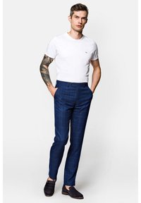 Niebieskie spodni w kratę o slim fit, noszone z białą koszulką z okrągłym dekoltem, uzupełnione ciemnoskórzanymi mokasynami. Posiada zapięcie na guzik.