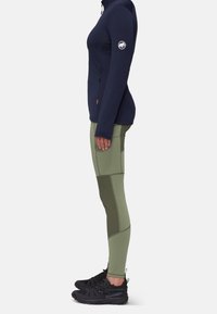 Marine blauwe zip-up jack, aansluitend ontwerp; olijfgroene leggings met contrasterende panelen; zwarte wandelschoenen met een gestructureerde grip; minimalistische details.