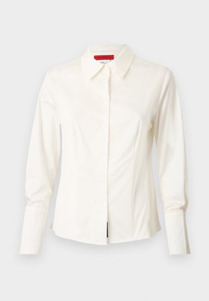 Camicia bianca con colletto in tessuto morbido, con maniche lunghe, chiusura a bottoni e una vestibilità scolpita con leggere pince frontali per dare forma.