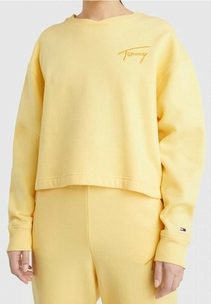 Gul cropped sweatshirt lavet af blød stof, har et diskret broderet logo på venstre bryst, med ribbet halsudskæring og manchetter.