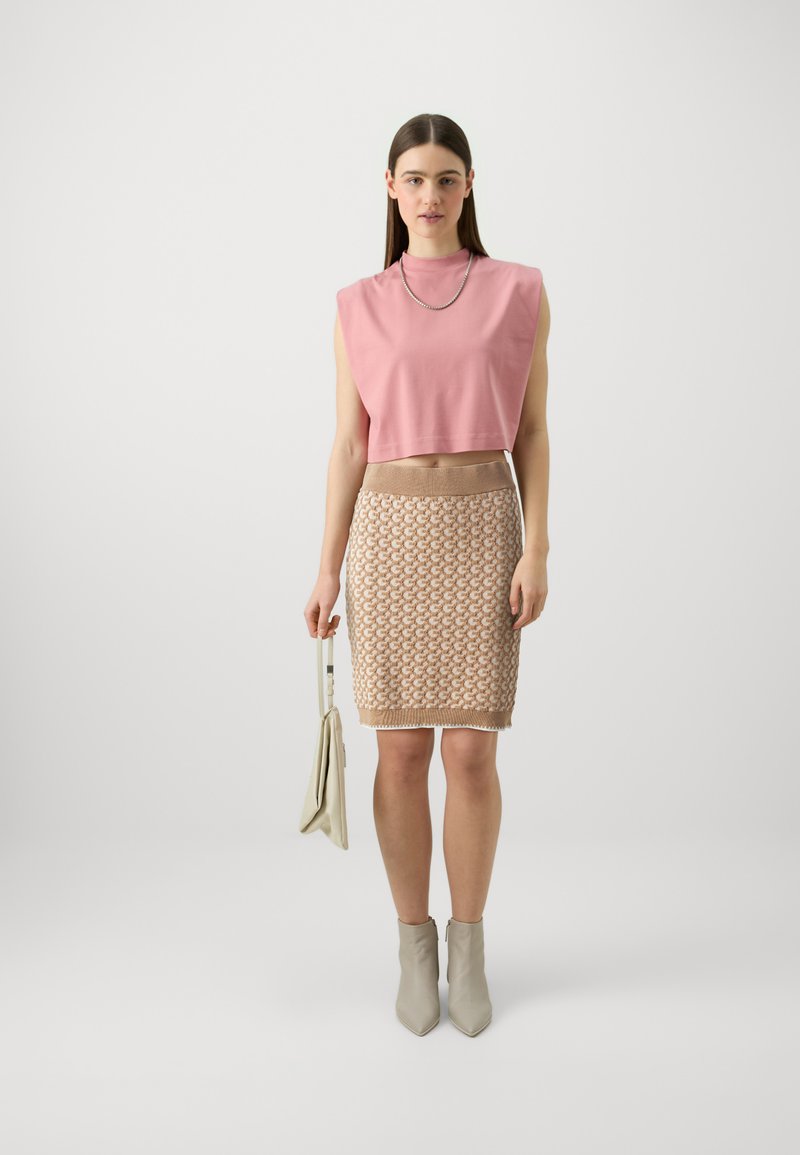 Rosa croppte Bluse mit gepolsterten Schultern, strukturierter beiger Bleistiftrock, graue Knöchelstiefel und eine helle Handtasche. Schlichtes und modernes Design.