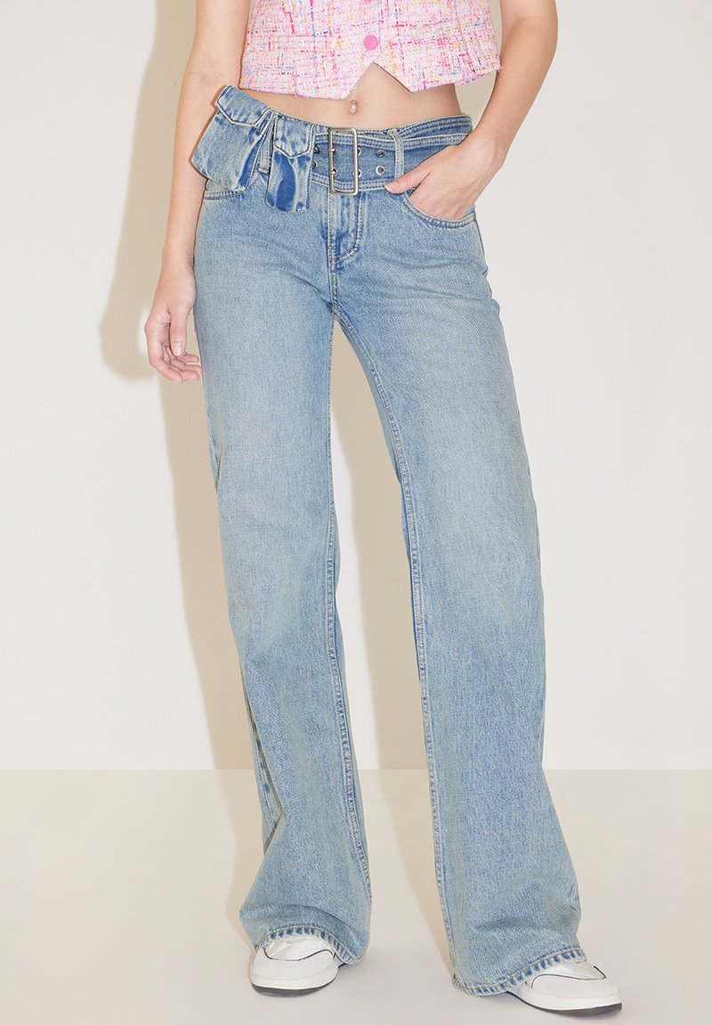 Jeans de tiro alto de pata ancha en azul claro, con un lazo y hebilla de metal. Textura clásica de denim.