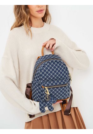 Sac à dos à motifs marins de forme arrondie, avec des zips dorés et une poignée en cuir marron. Équipé d'un porte-clés en forme d'ours.