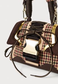 Geantă houndstooth în nuanțe de brown și bej, cu o cataramă aurie și mânere texturate, având o bază netedă și detalii decorative de dantelare.