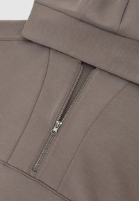 Sudadera con capucha en tela marrón-gris; cuenta con una cremallera parcial con herrajes metálicos y un diseño ajustado. Textura suave con un acabado liso.