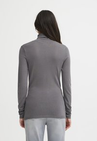 Pieguļošs pelēks garām piedurknēm turtlenecks džemperis ar ribotām aprocēm un apakšu, izgatavots no elastīga auduma, demonstrējot gludu tekstūru.