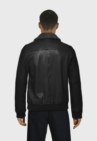 Chaqueta de cuero negra con un collar de piel sintética, puños y dobladillo acanalados, con un acabado suave y un ajuste entallado en la parte posterior.