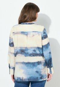 Langarm button-up shirt in een blauw en crème tie-dye patroon, met een rechte zoom, kraag en manchetten met knopen. Glad textuur van de stof.