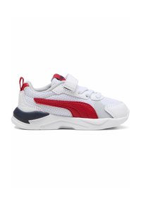 Des chaussures de sport blanches présentent une tige en mesh avec des accents rouges et marins, une sangle en Velcro et une épaisse semelle blanche avec des détails texturés.