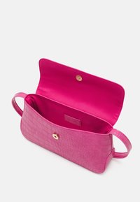 Różowa torba z tłoczonej skóry krokodyla, z gładkim wnętrzem, zapięciem na zatrzask i dwoma uchwytami. Wnętrze wyściełane jest żywym różowym satynem.