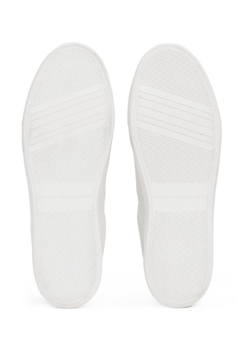 Białe gumowe podeszwy butów z poziomymi rowkami dla lepszej przyczepności. Zawierają wytłoczone logo "TOMMY HILFIGER" w pobliżu pięty. Gładka tekstura.