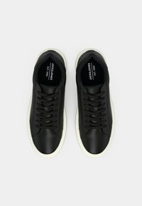 Pair of black leather sneakers with white soles and black laces, top view, branded JACK & JONES inside sole.